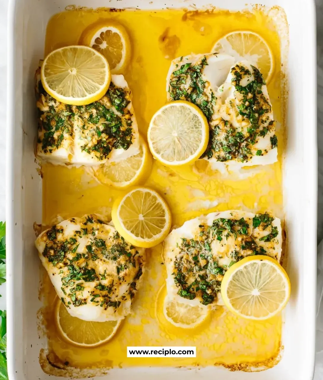 Garlic Herb Baked Cod served with fresh herbs and lemon wedges