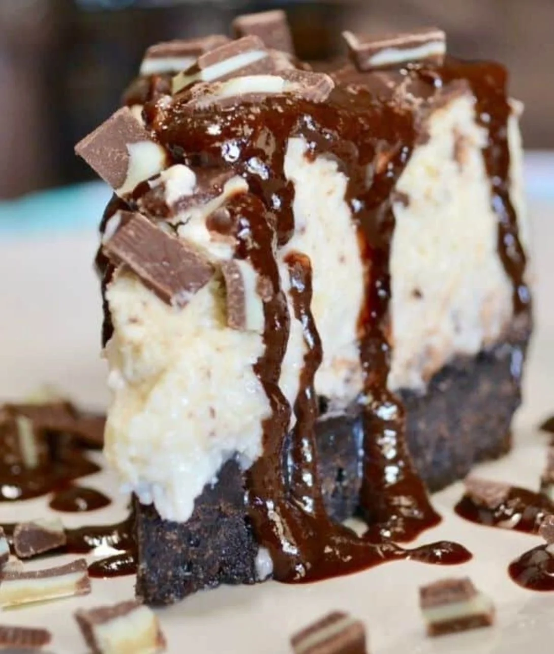 Slice of Andes Mint Cheesecake topped with mint leaves and chocolate drizzle