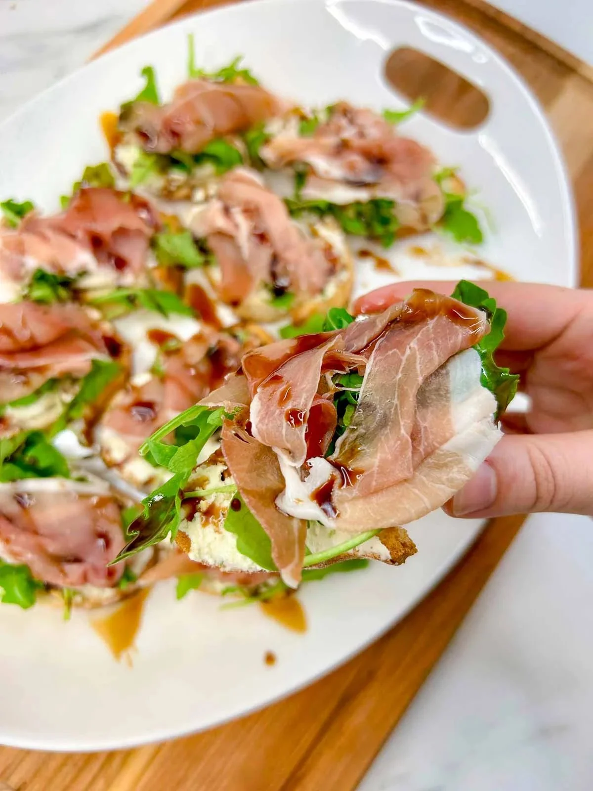 Boursin prosciutto arugula crostini appetizer on a rustic platter