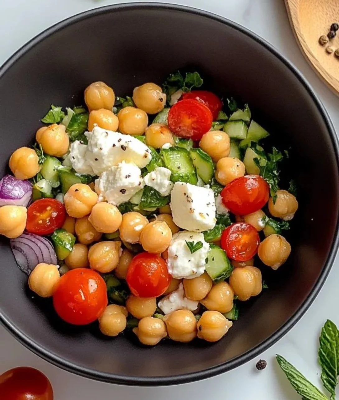 Bowl of Cottage Cheese and Chickpeas Salad with fresh vegetables and dressing.
