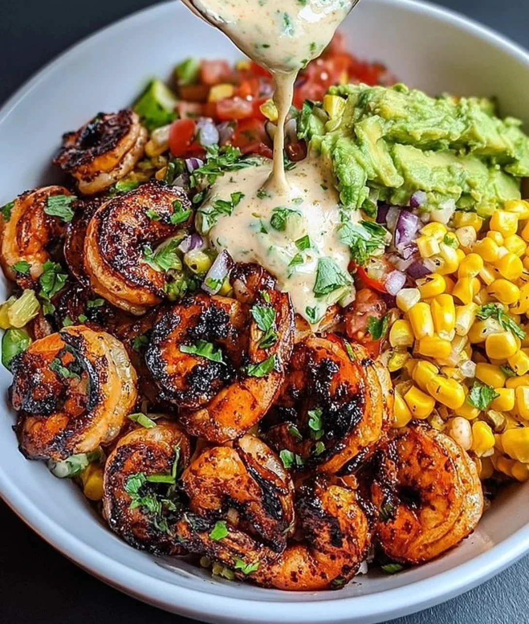 Delicious grilled shrimp bowl with avocado, corn salsa, and creamy garlic sauce