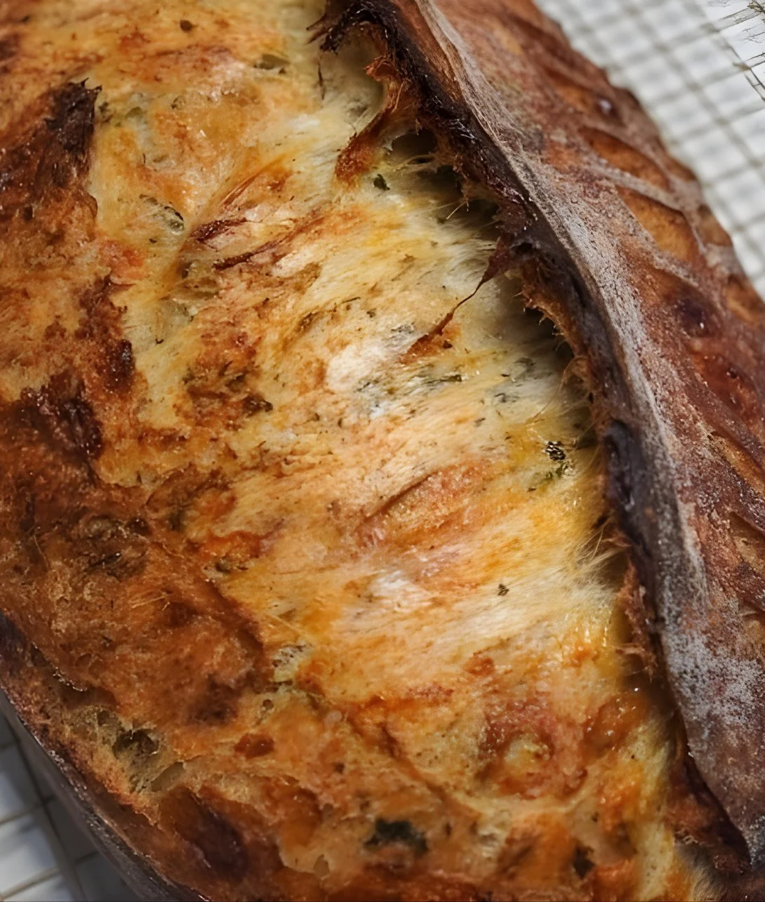 Loaf of Italian Herbs & Cheese Artisan Sourdough Bread on a wooden board