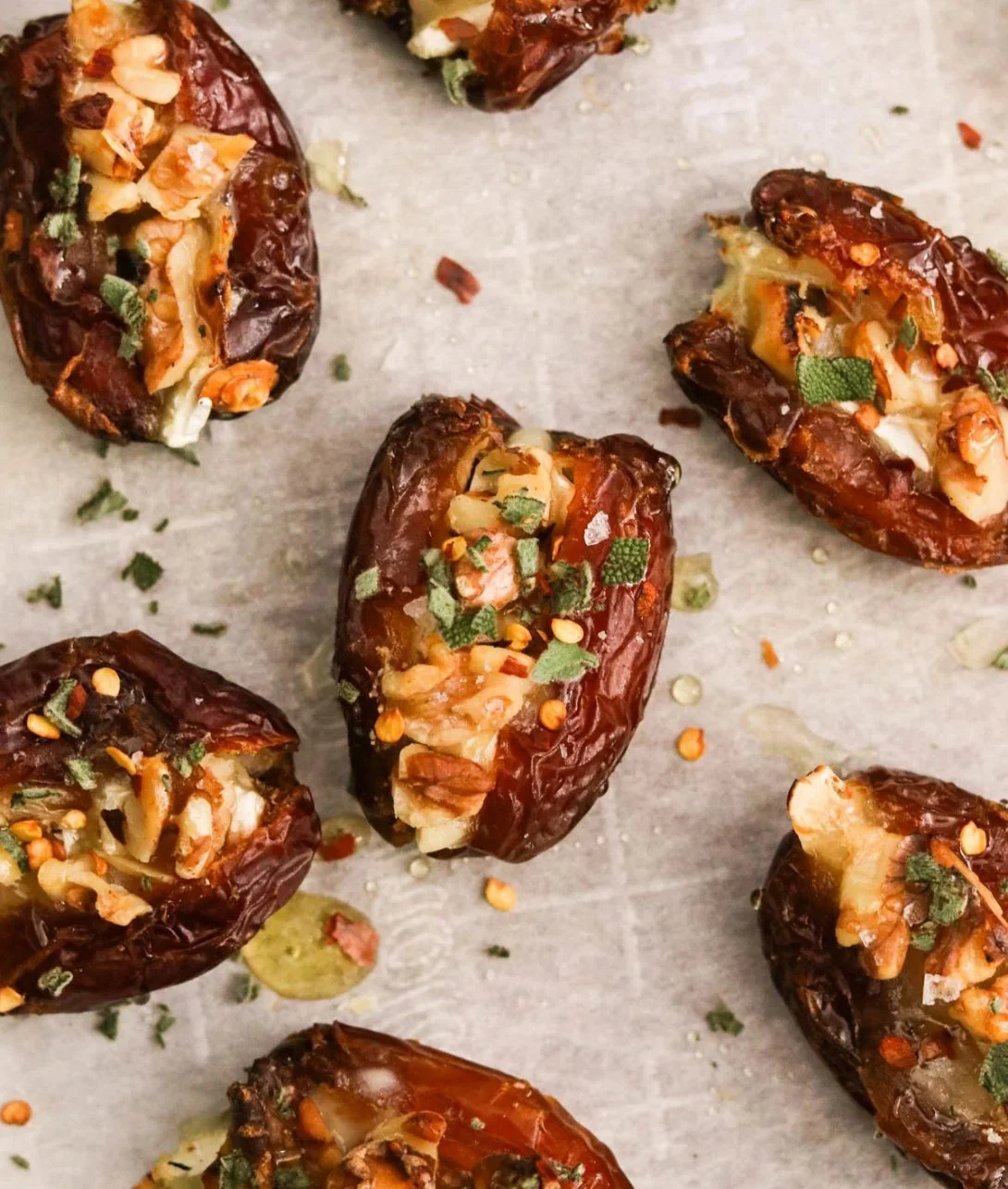 Air Fryer Brie Stuffed Dates topped with nuts and herbs, served on a wooden platter.