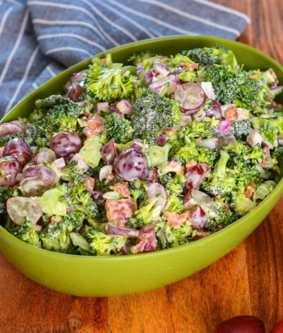 Bowl of colorful broccoli salad with grapes and nuts garnished with dressing