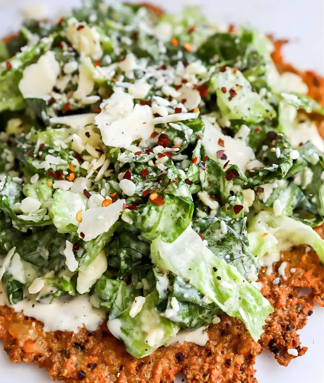 Delicious Chicken Crust Caesar Salad Pizza topped with fresh greens and Caesar dressing.