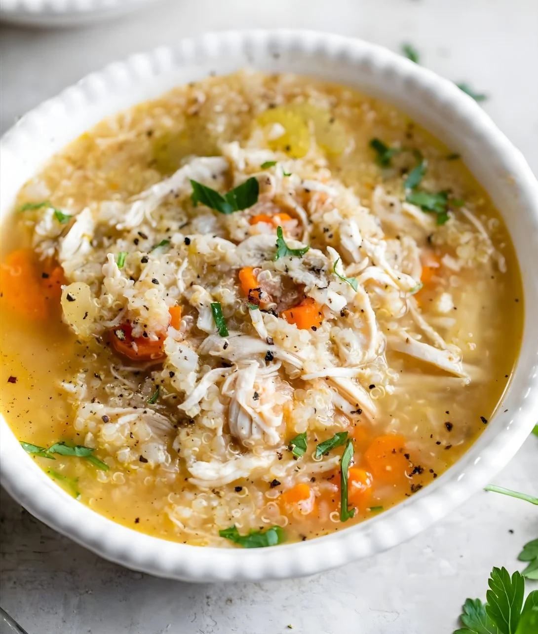 Bowl of Chicken Quinoa Soup garnished with herbs and spices