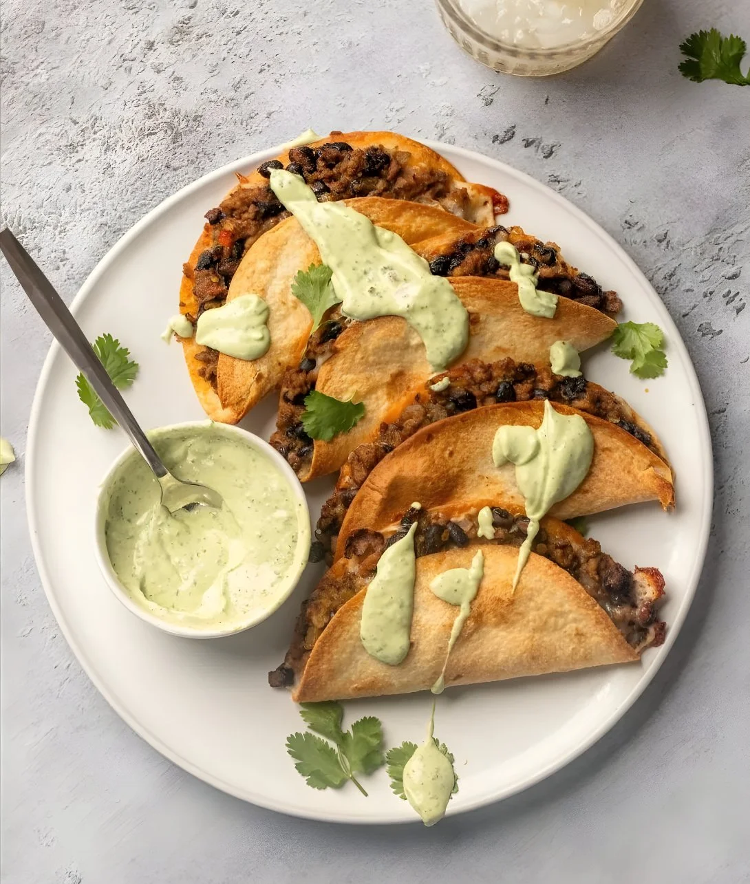 Crispy baked ground turkey tacos served with avocado sauce on a plate.
