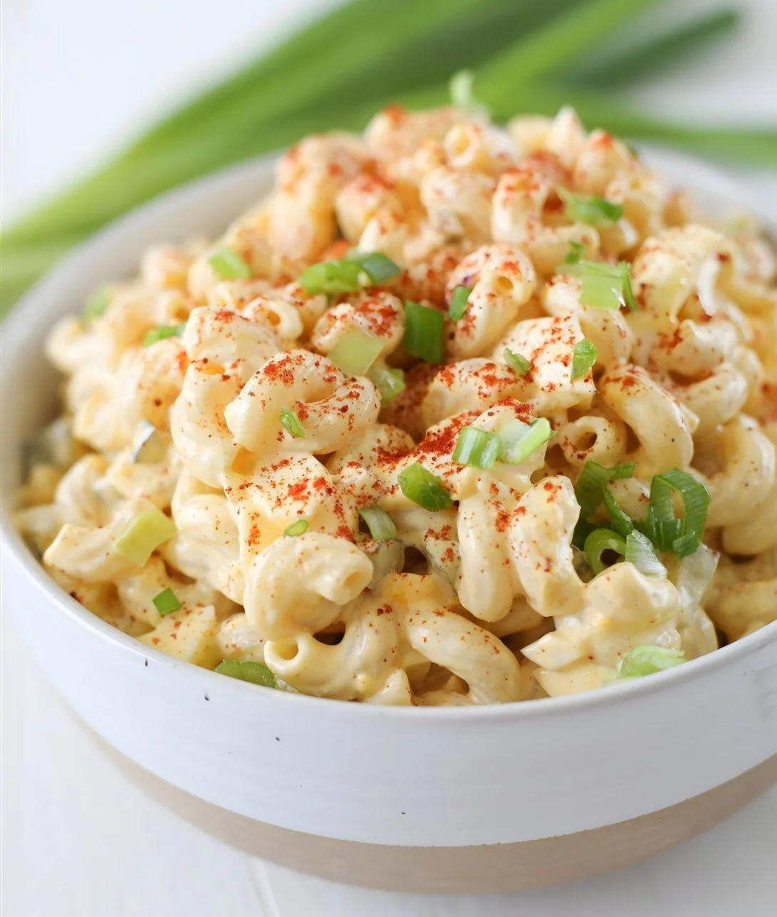 Delicious deviled egg pasta salad garnished with herbs in a serving bowl