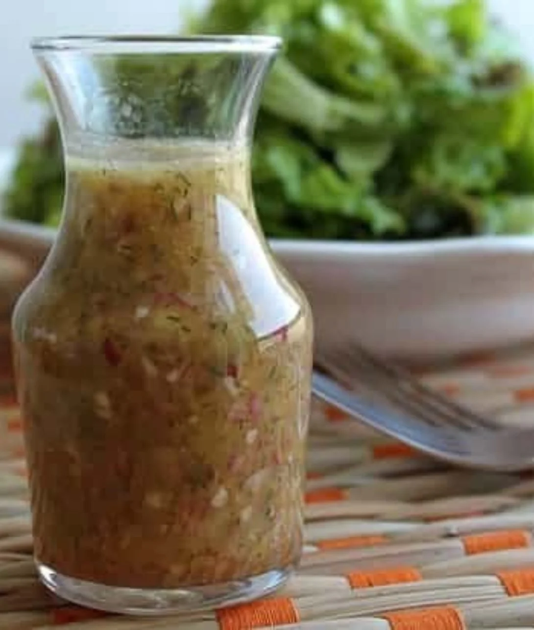 Dill Red Onion Dressing in a small bowl with fresh herbs and onions