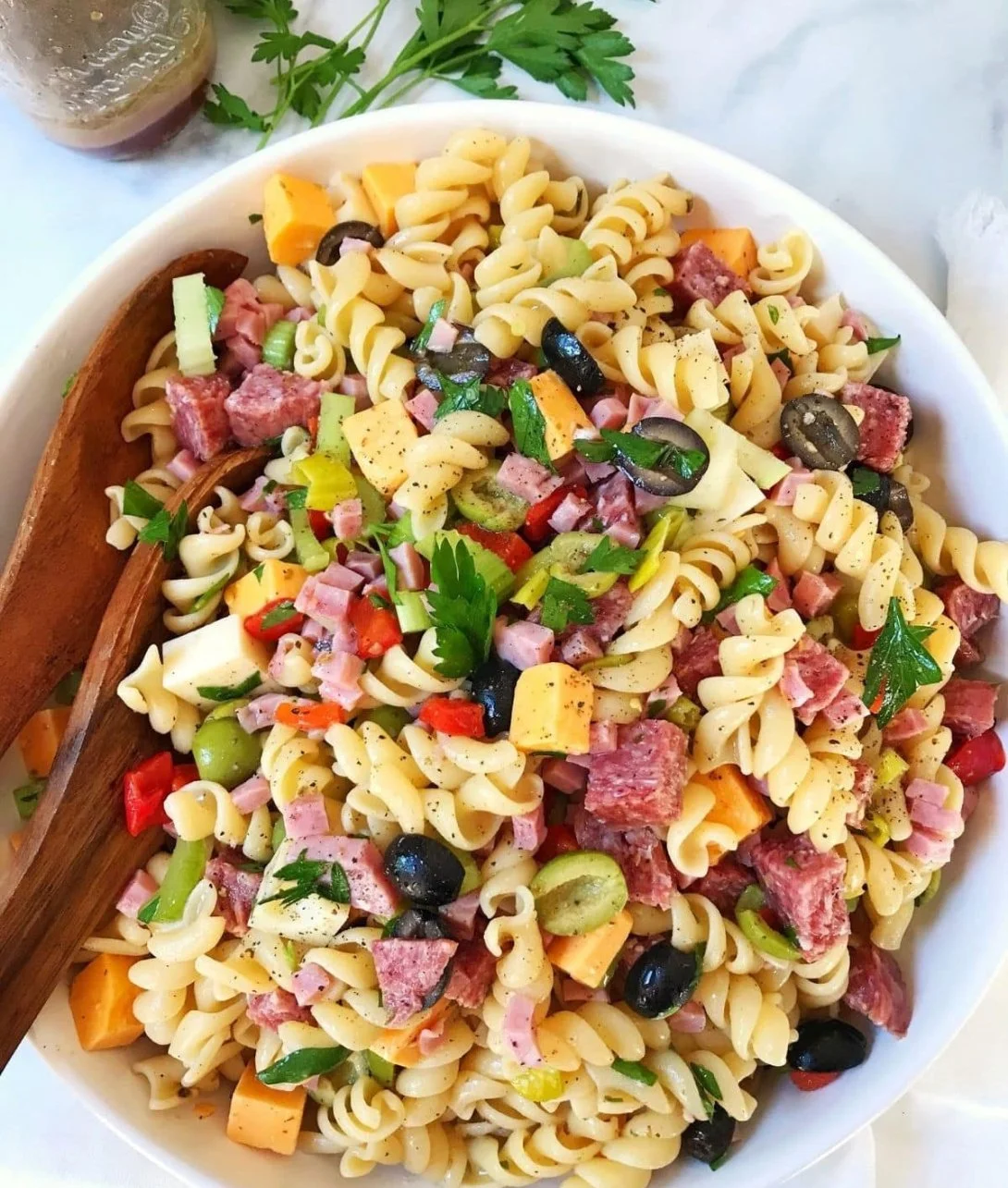 A colorful bowl of easy muffuletta pasta salad with olives, salami, and cheese.