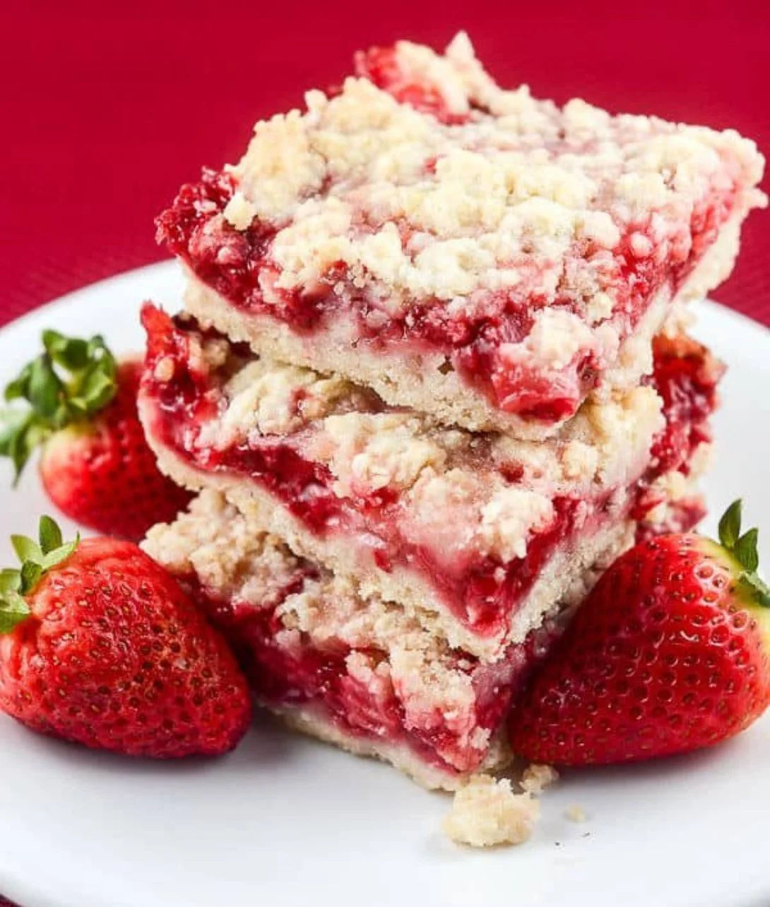 Delicious easy strawberry crumb bars on a plate with fresh strawberries