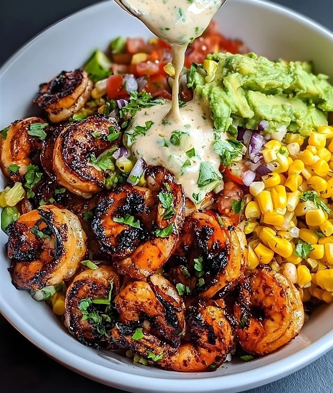 Delicious grilled shrimp bowl with avocado, corn salsa, and creamy garlic sauce