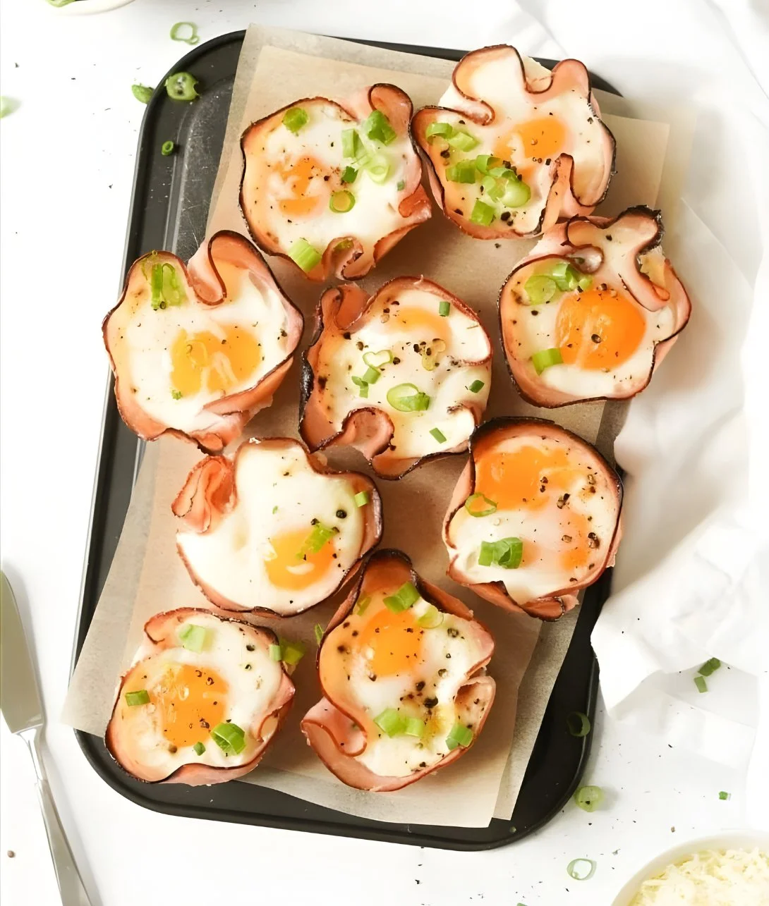 Ham and cheese egg cups served in a muffin tray, perfect for breakfast