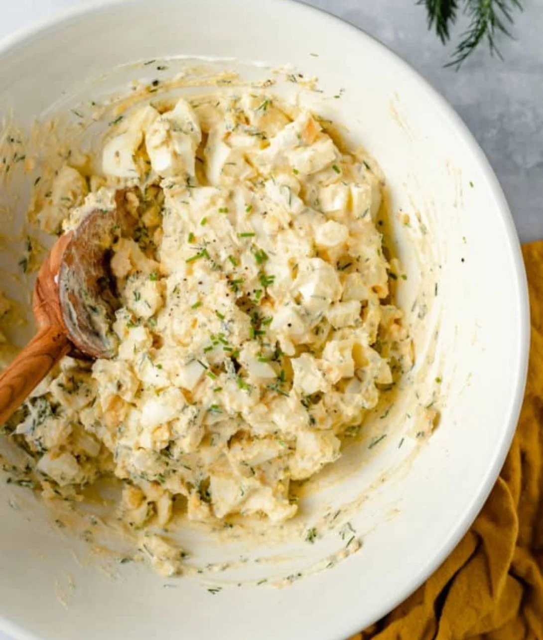 Healthy egg salad served in a bowl with fresh herbs and ingredients.