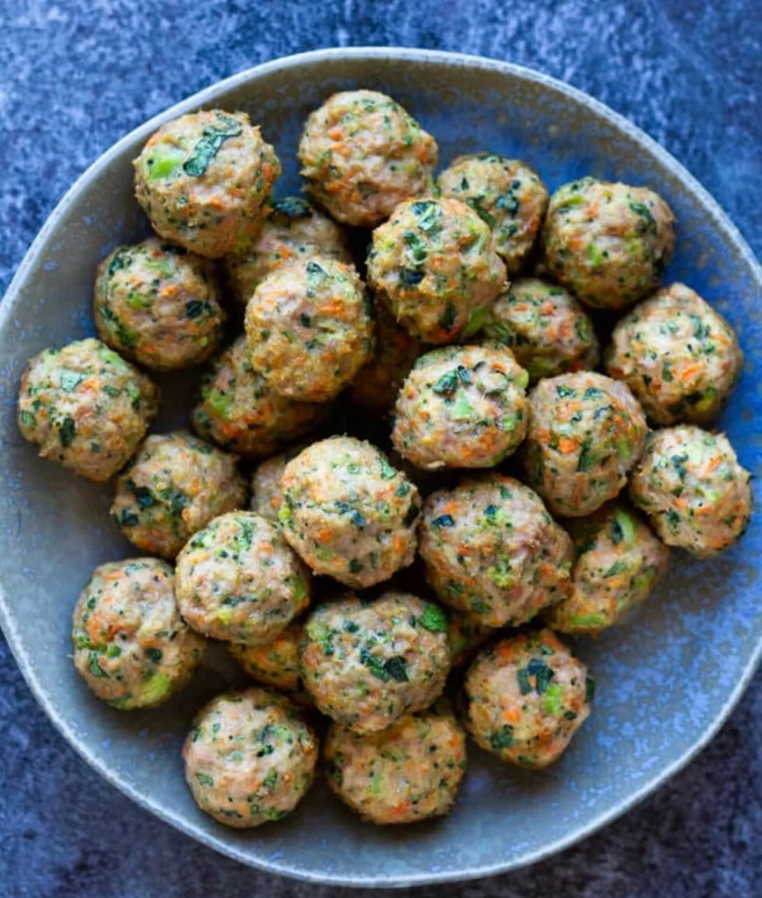 Loaded veggie turkey meatballs gluten free served on a plate with fresh herbs.