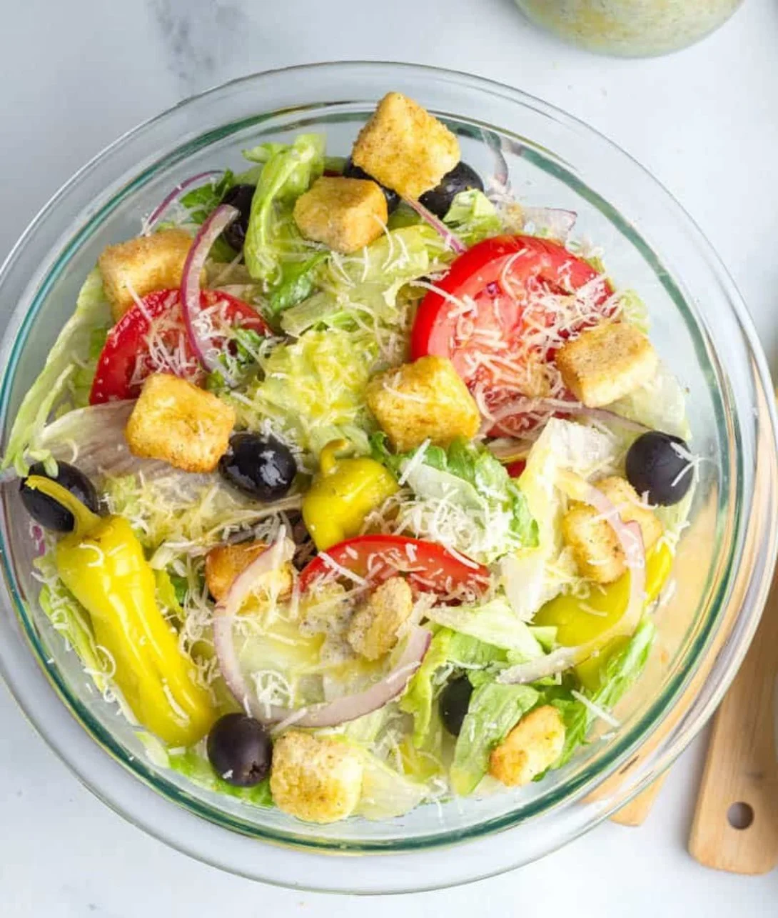 A bowl of fresh Olive Garden Salad with crisp greens, olives, and cheese.