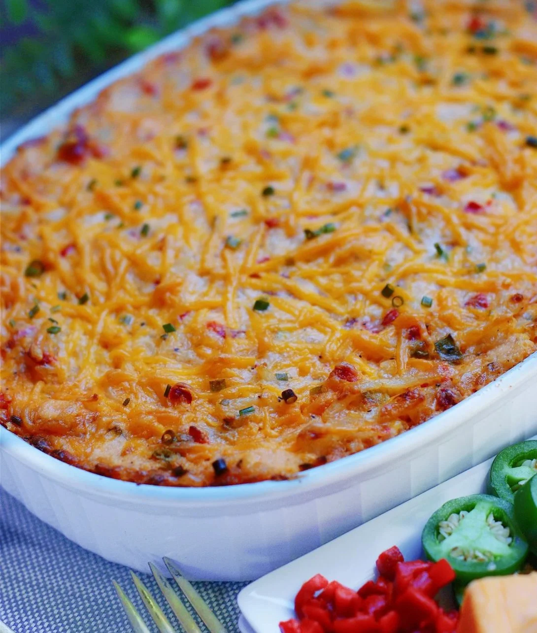 Pimento Cheese Hash Brown Casserole served in a dish, garnished with herbs.