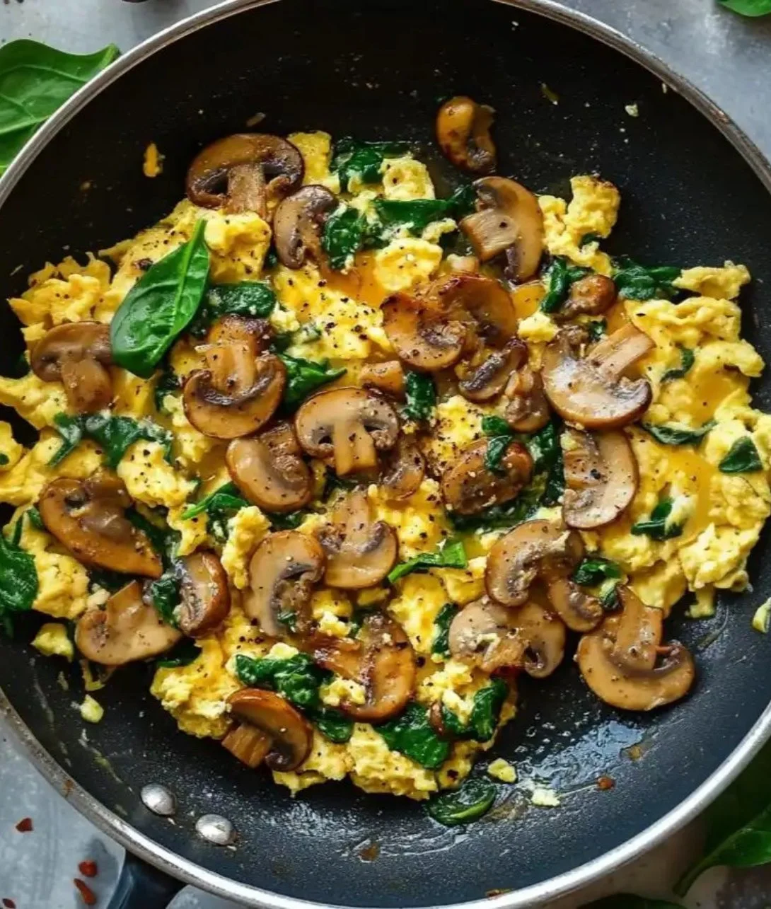 Delicious mushroom spinach scrambled eggs cooked in a skillet