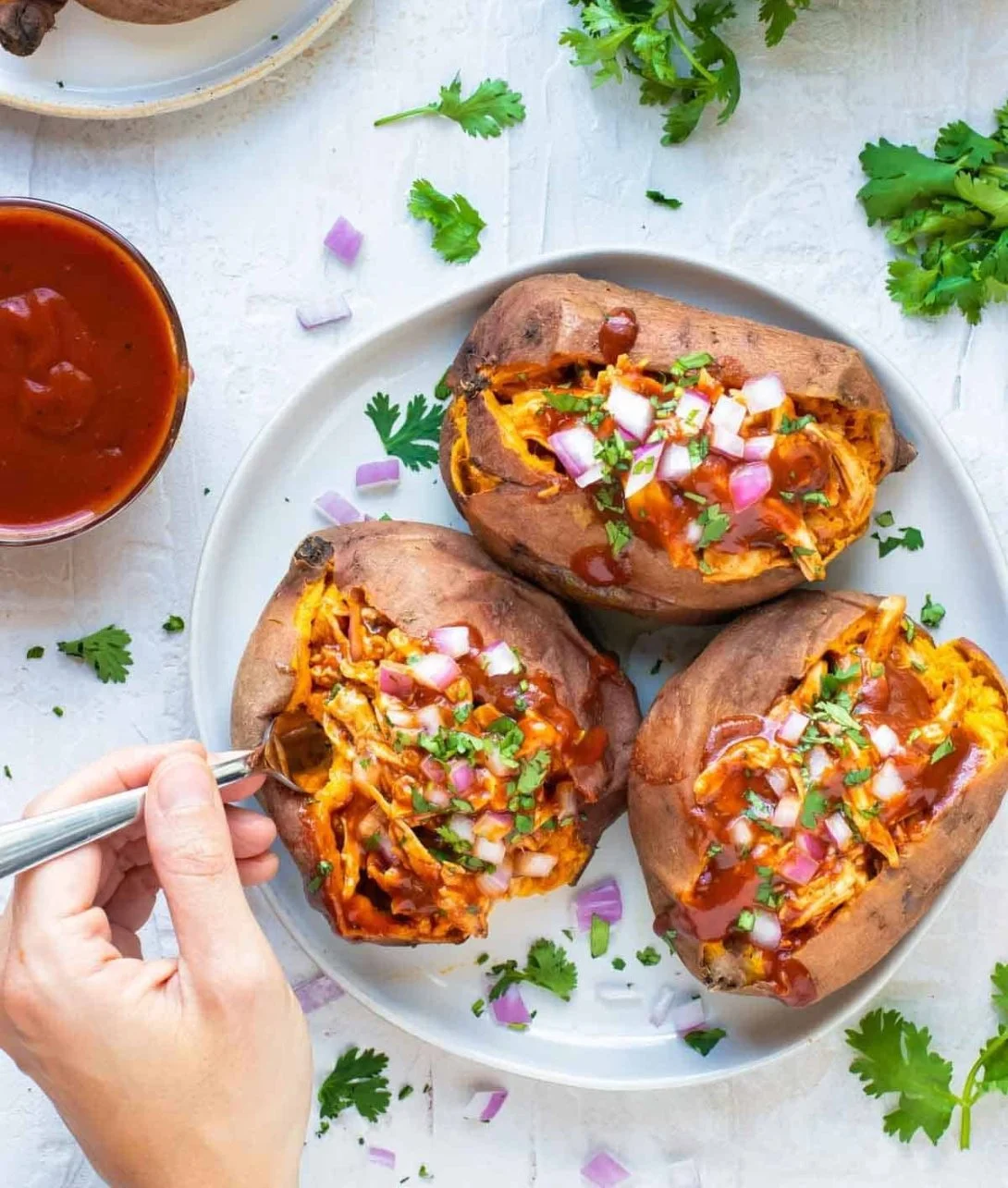 BBQ chicken stuffed sweet potatoes topped with green onions and sauce