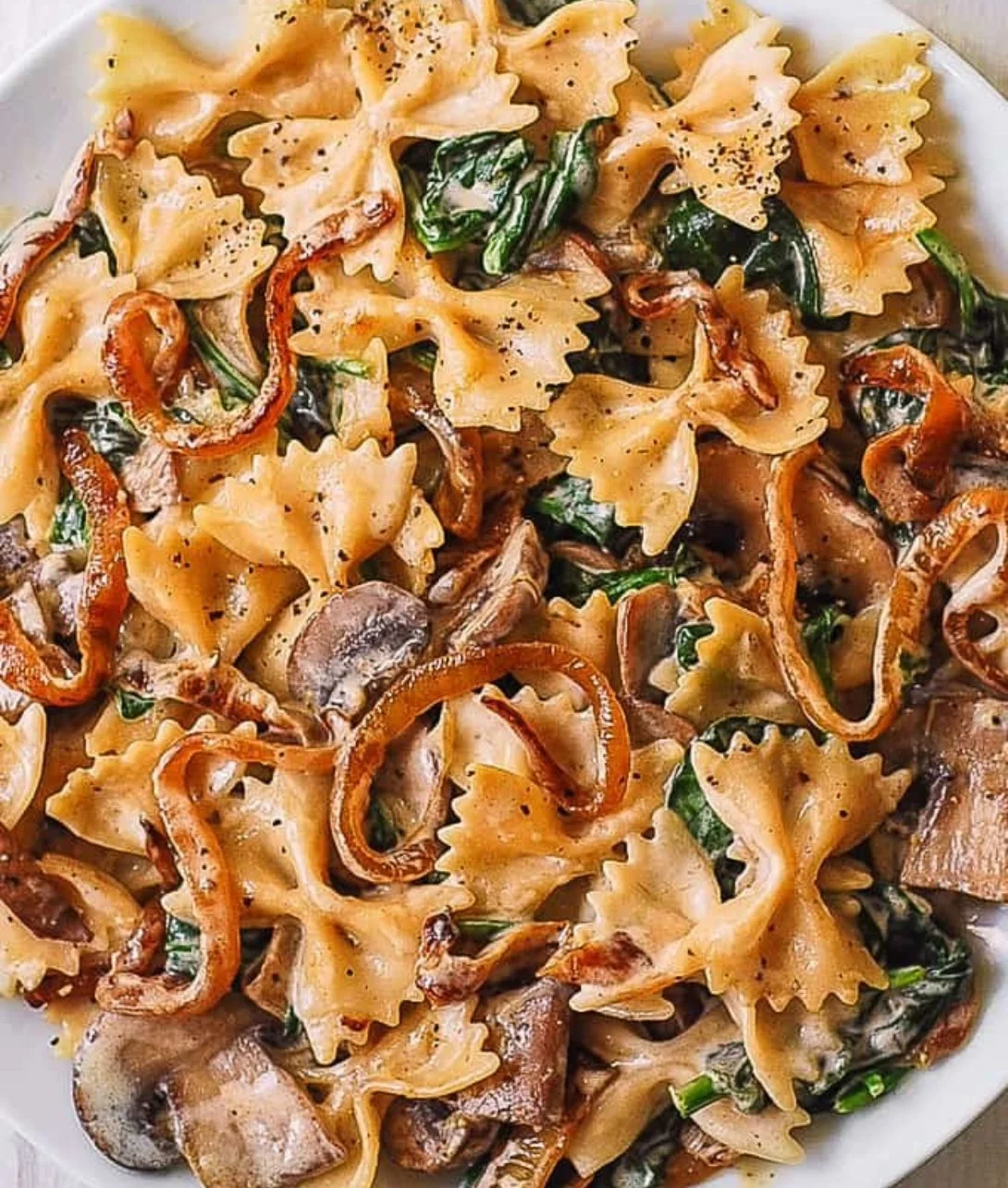Bowtie pasta with spinach, mushrooms, and caramelized onions in a delicious dish