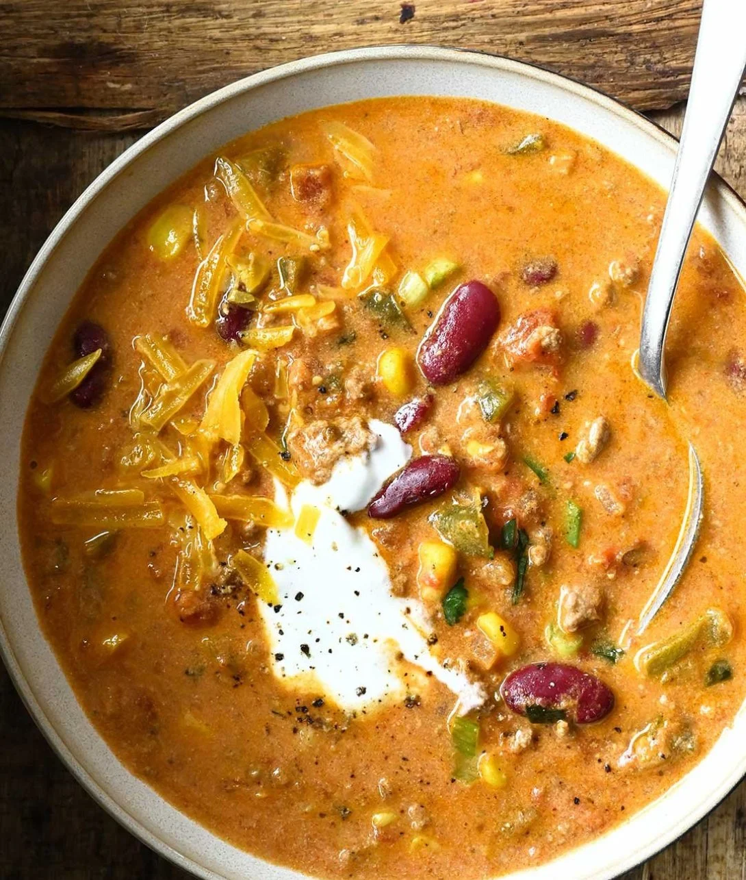Bowl of creamy beef taco soup garnished with cheese and cilantro