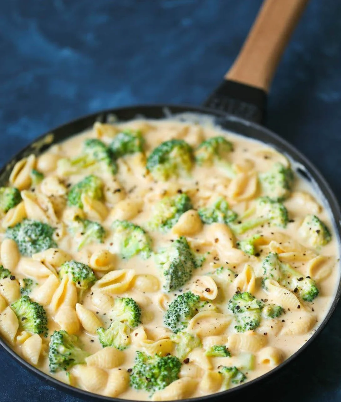 Creamy broccoli mac and cheese dish topped with cheese and broccoli florets.