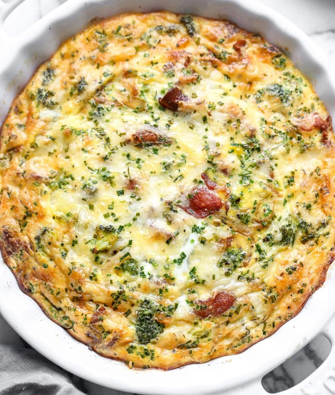 Delicious slice of Crustless Quiche with vegetables and cheese on a plate.