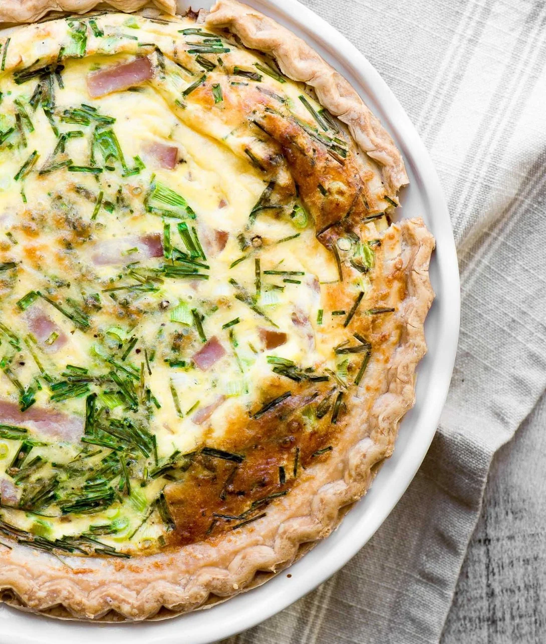 Eggs Benedict Quiche topped with rich Hollandaise sauce, served on a plate