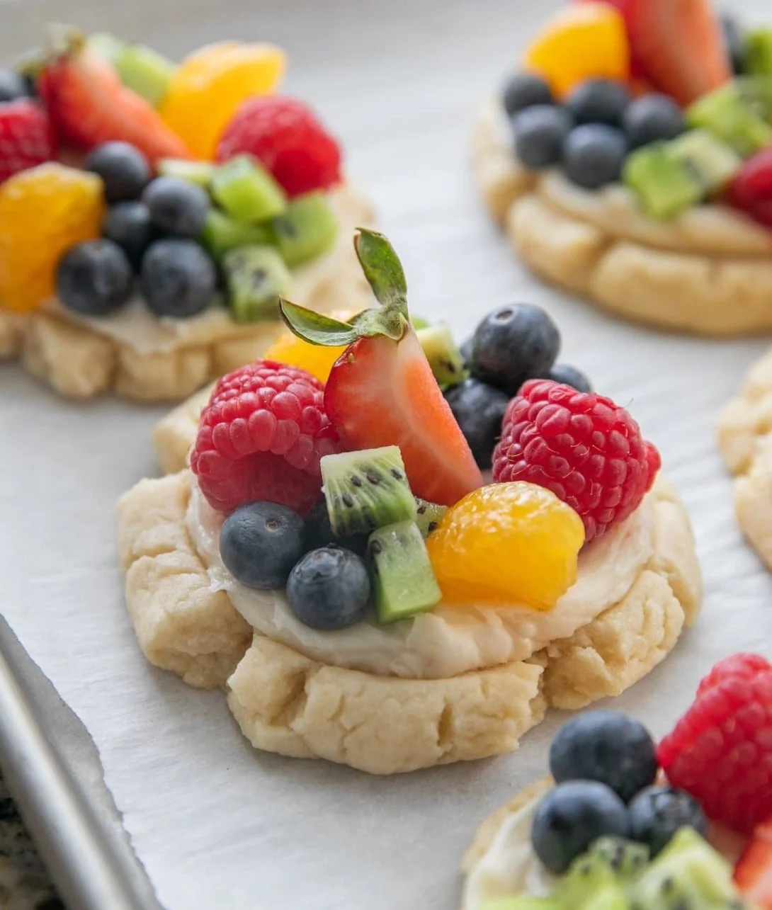 Delicious fruit pizza cookies topped with fresh fruit and creamy frosting.