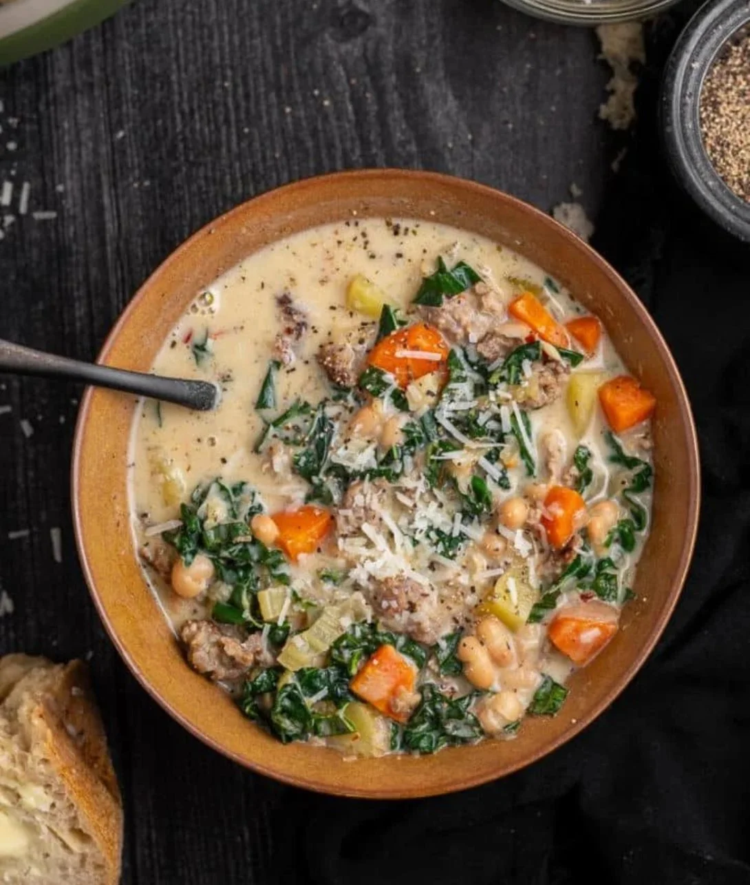 A bowl of Italian sausage and white bean soup garnished with herbs.