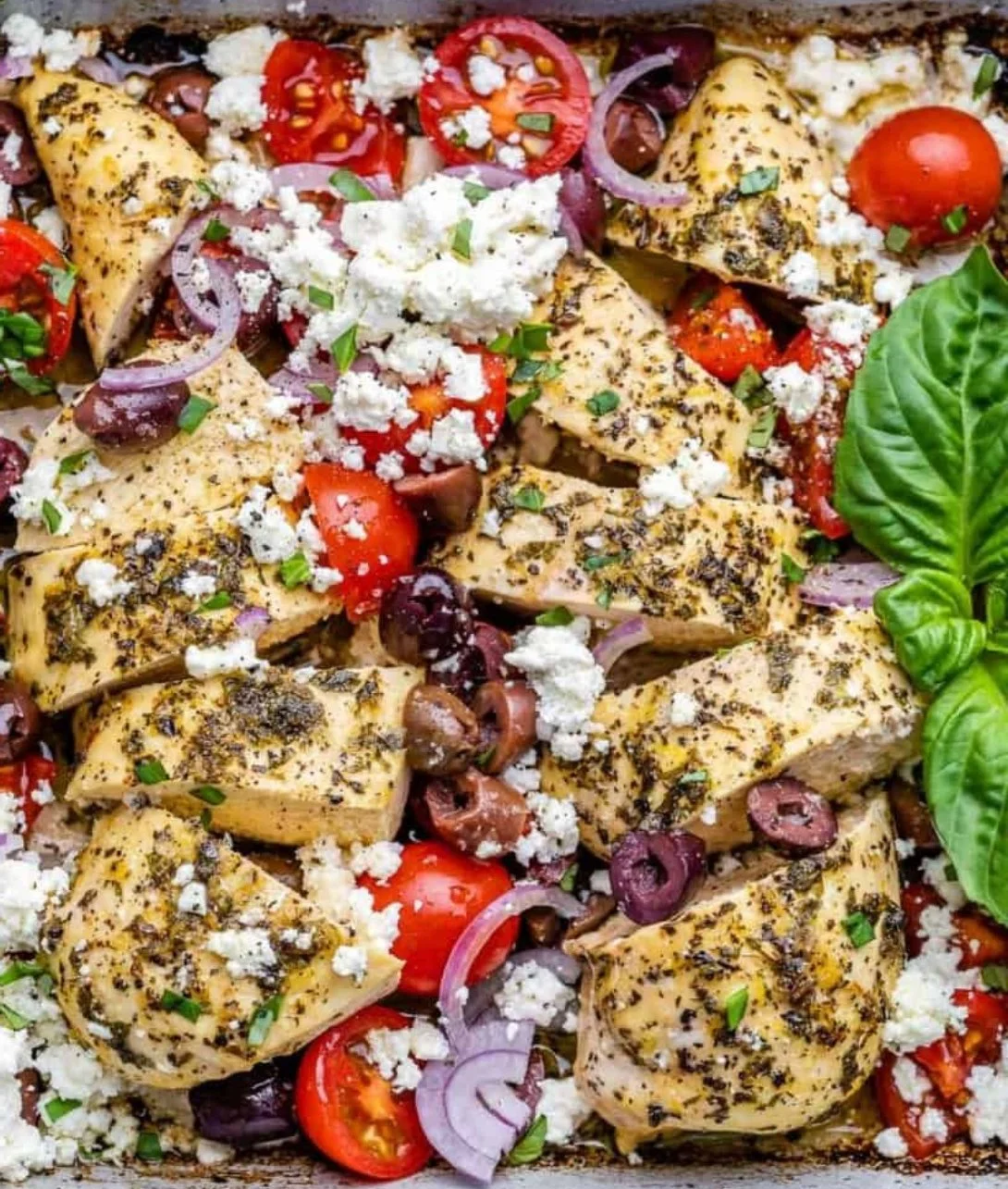 Oven-baked Greek chicken breast garnished with herbs and lemons