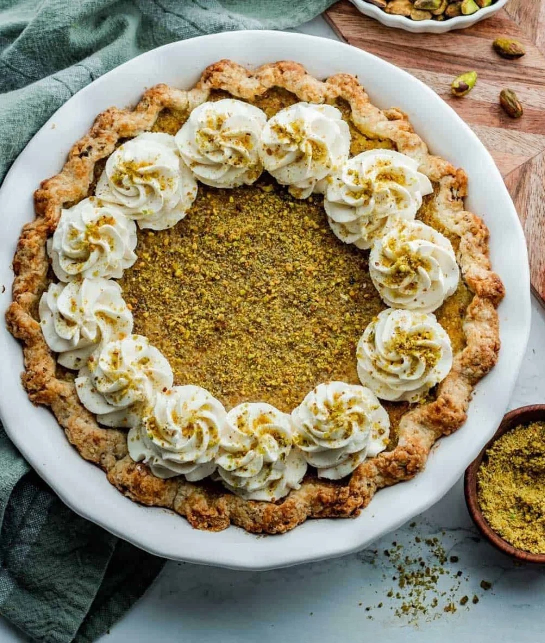 Slice of homemade pistachio custard pie topped with whipped cream and nuts