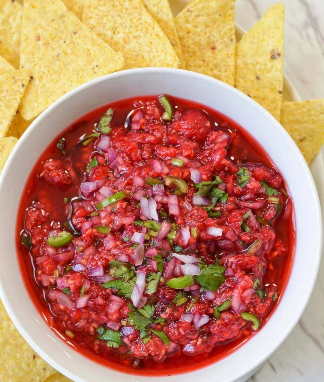 Bowl of homemade Raspberry Salsa with fresh raspberries and herbs.
