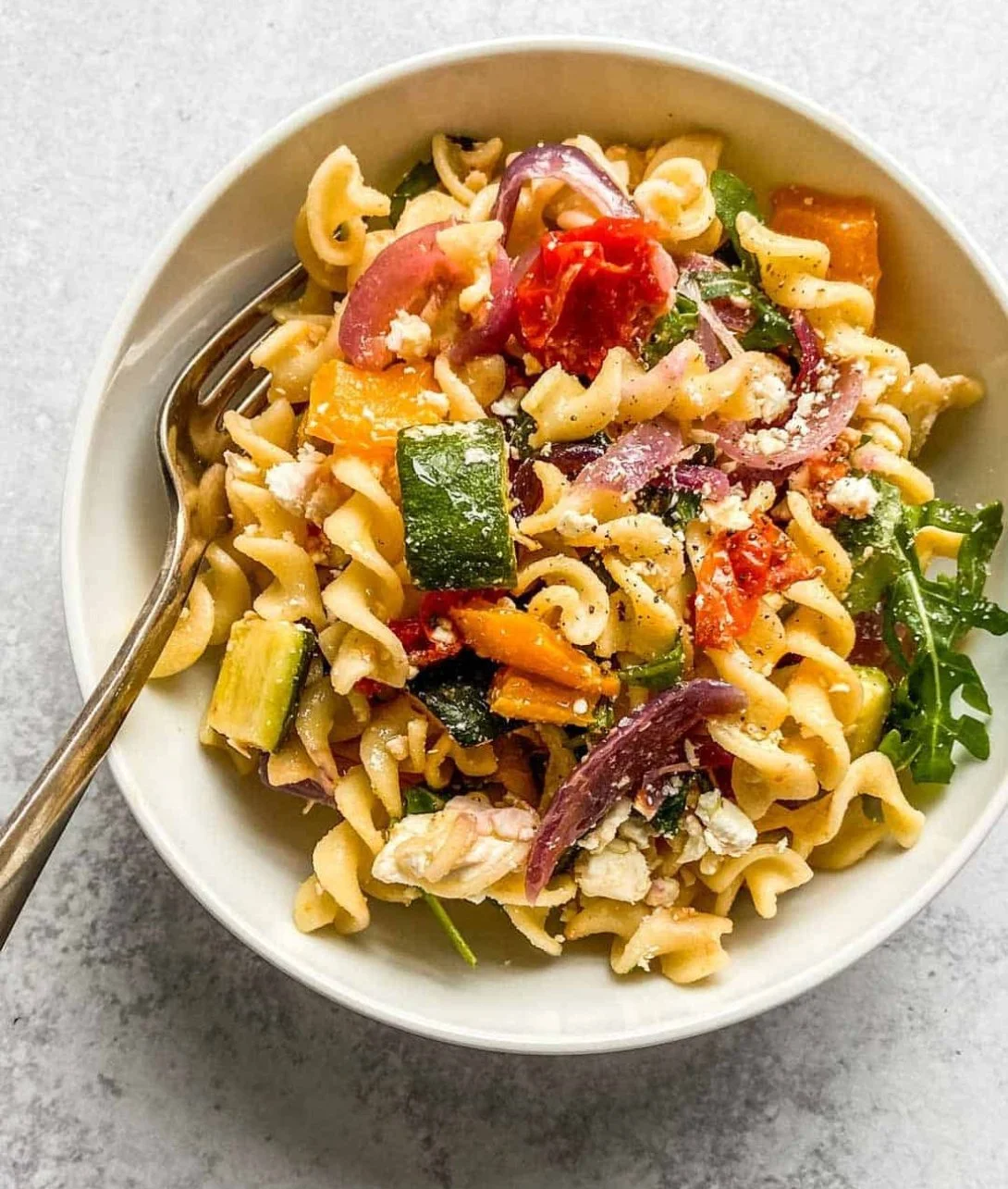 Roasted veggie pasta with feta and colorful vegetables in a bowl