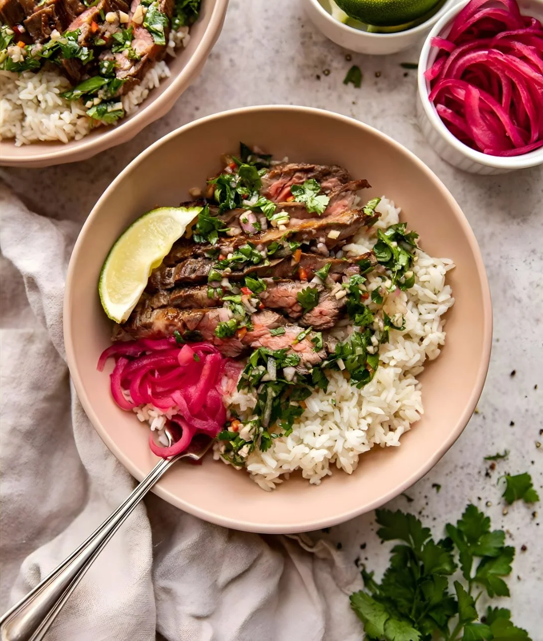 Skirt steak rice bowl topped with chimichurri sauce and fresh vegetables