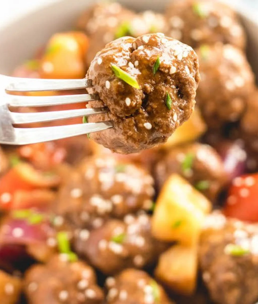 Slow cooker sweet and sour meatballs served in a bowl with sauce and garnish