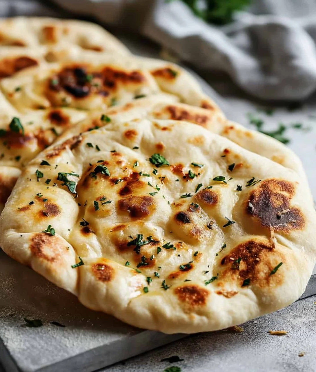 Freshly baked garlic naan bread, golden and fluffy, served with curry.