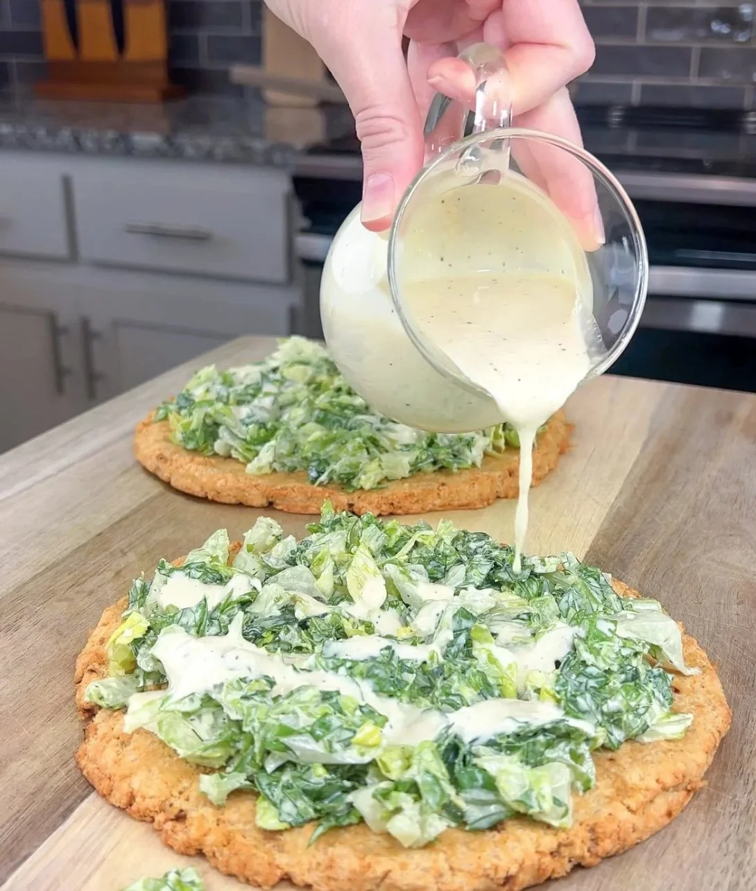 Viral Chicken Crust Caesar Salad Pizza topped with fresh ingredients