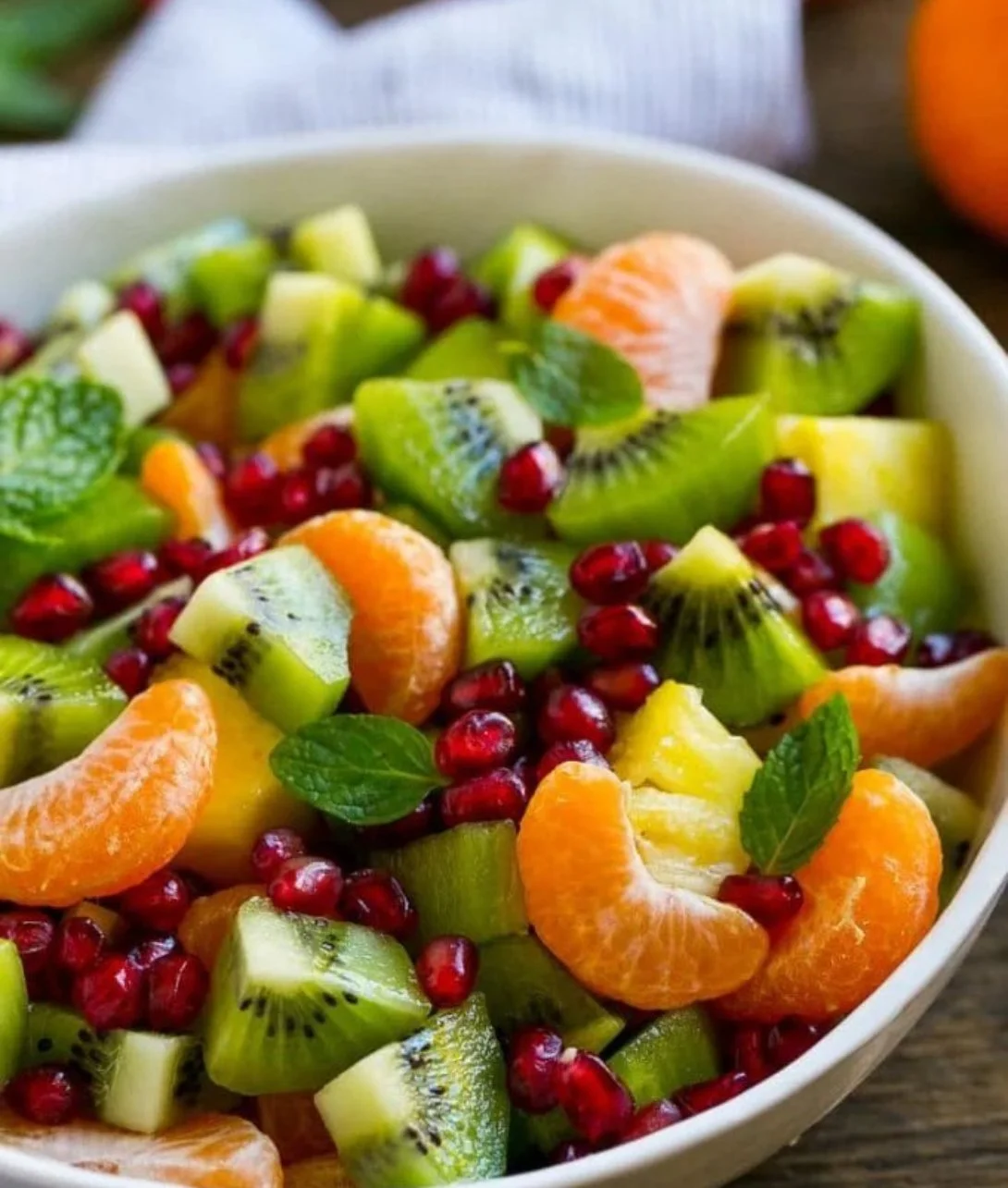 Colorful winter fruit salad with seasonal fruits like pomegranate, oranges, and kiwi.