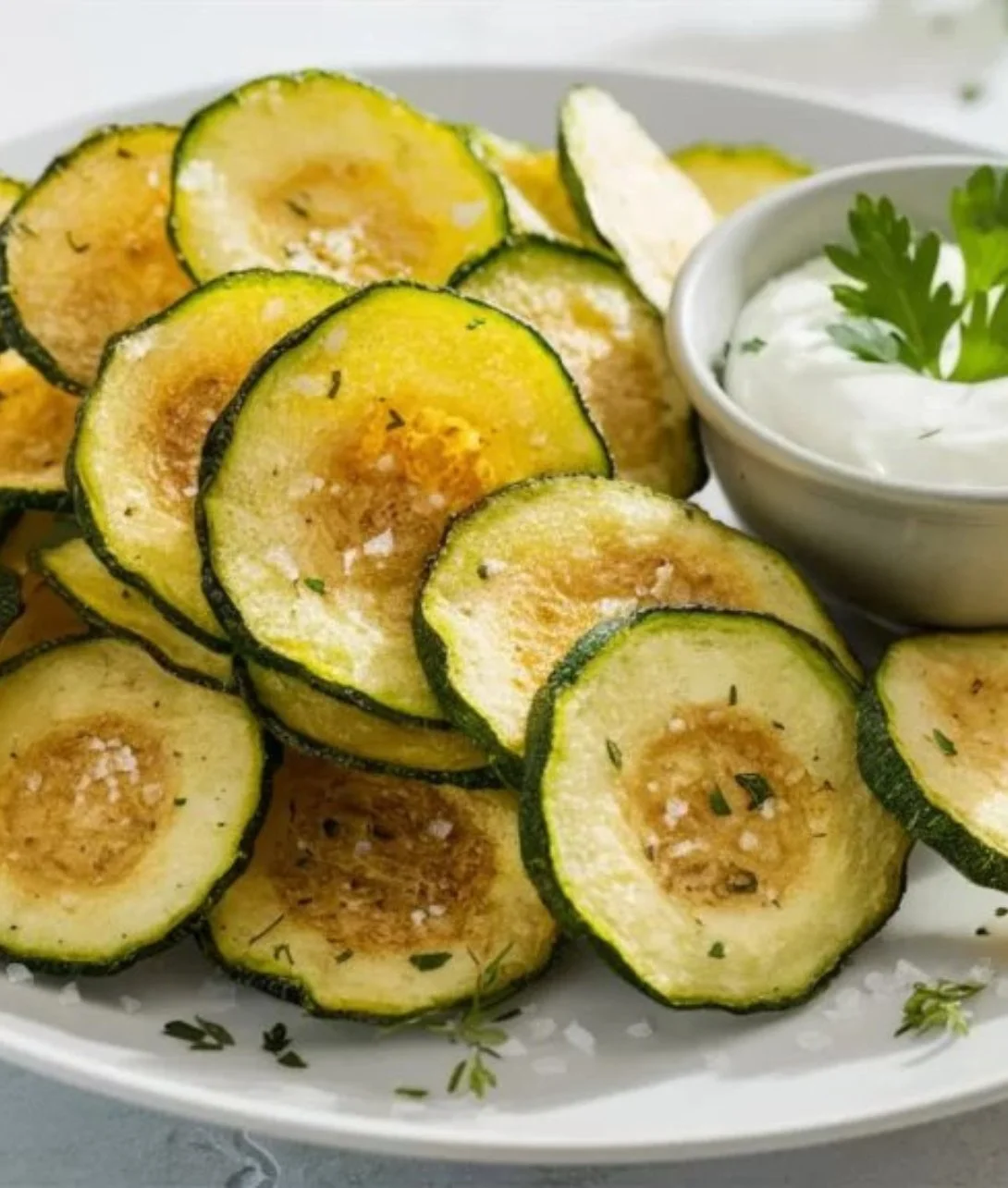 Crispy air fryer zucchini chips on a plate, perfect healthy snack option.