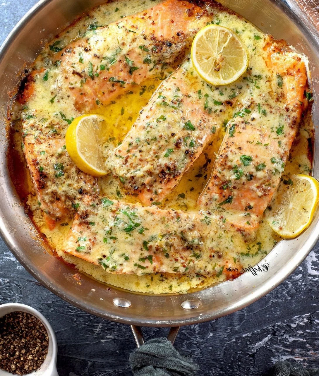 Baked salmon fillet drizzled with lemon butter cream sauce on a plate.