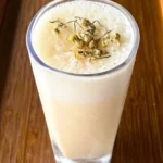 Banana chamomile tea smoothie served in a bowl with fresh bananas and chamomile flowers