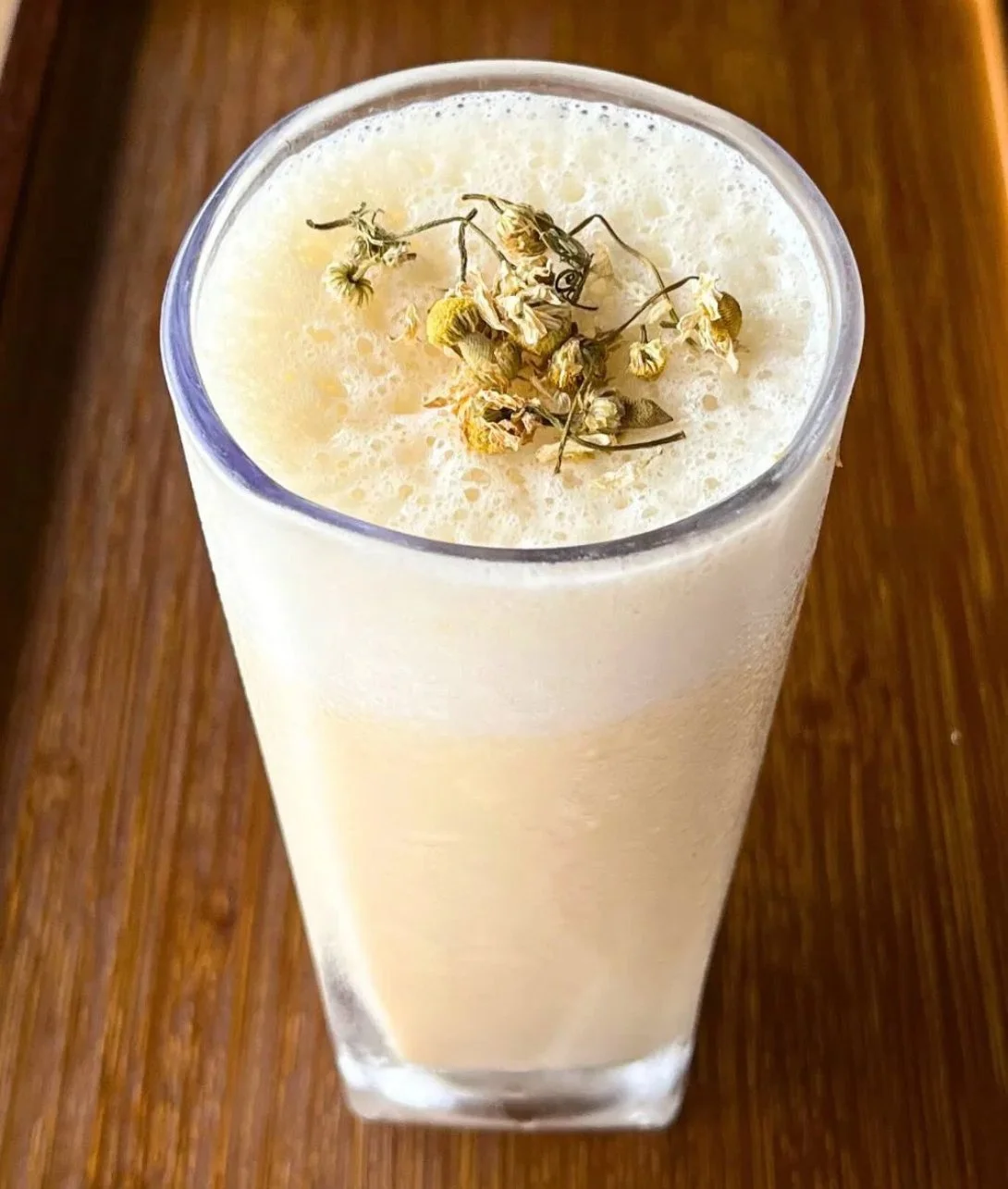 Banana chamomile tea smoothie served in a bowl with fresh bananas and chamomile flowers