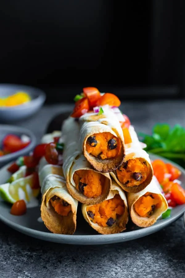 Baked black bean taquitos served with avocado and salsa.