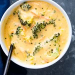 A bowl of creamy Broccoli Cheddar Soup with fresh broccoli and cheese.