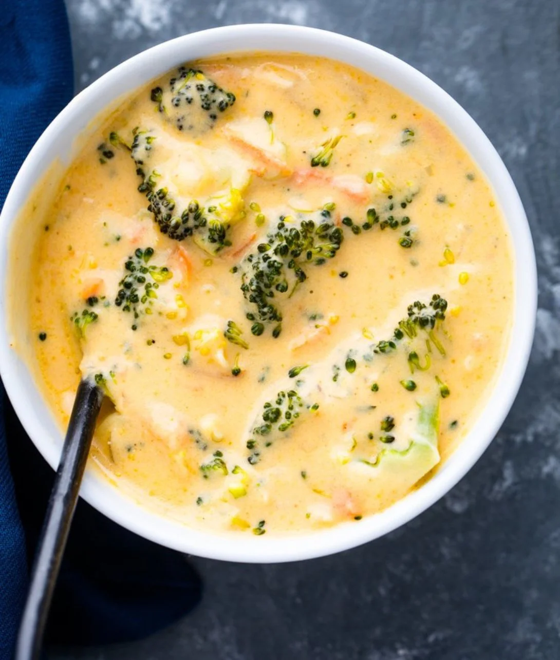 A bowl of creamy Broccoli Cheddar Soup with fresh broccoli and cheese.