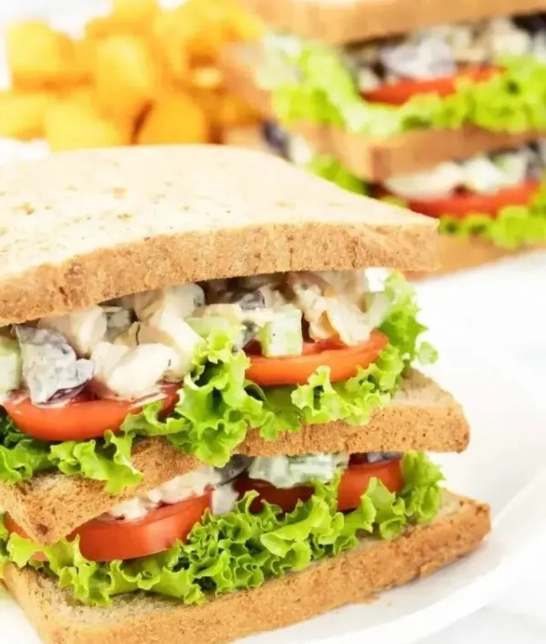 Tasty chicken salad sandwich served on a plate with fresh vegetables.
