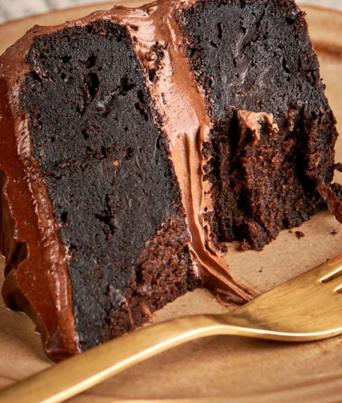 Delicious slice of chocolate zucchini cake with frosting and fresh zucchini on the side