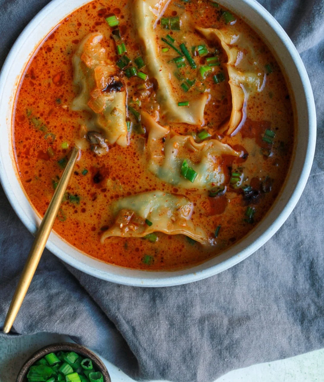 Bowl of Coconut Curry Soup with Dumplings garnished with fresh herbs