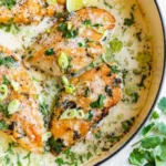 Creamy coconut lime chicken garnished with lime slices and herbs